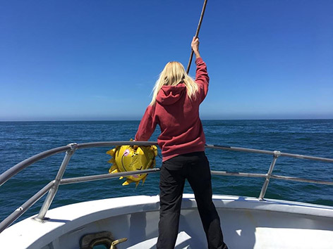 a person standing in front of a boat next to a body of water